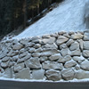 Sheer rock face in large stone blocks with metal protection and turf.